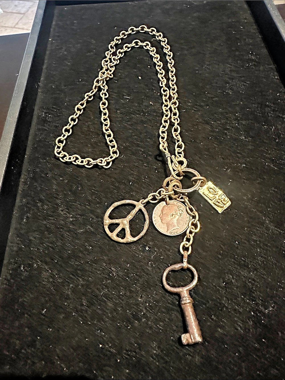 Gold tone necklace with love, peace coin and key charms